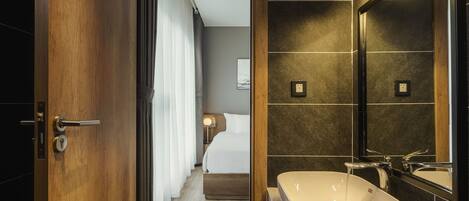 A modern bathroom with a large sink, a mirror, and a shower.