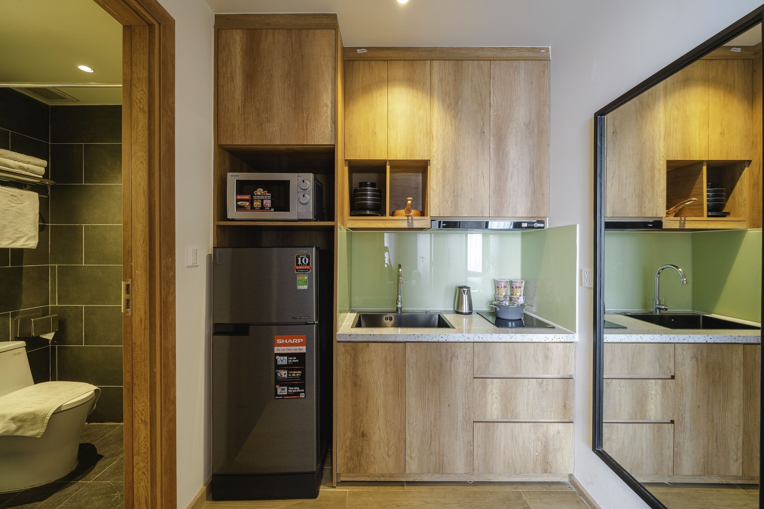 A compact kitchen with wooden cabinets, a built-in microwave, and a refrigerator.