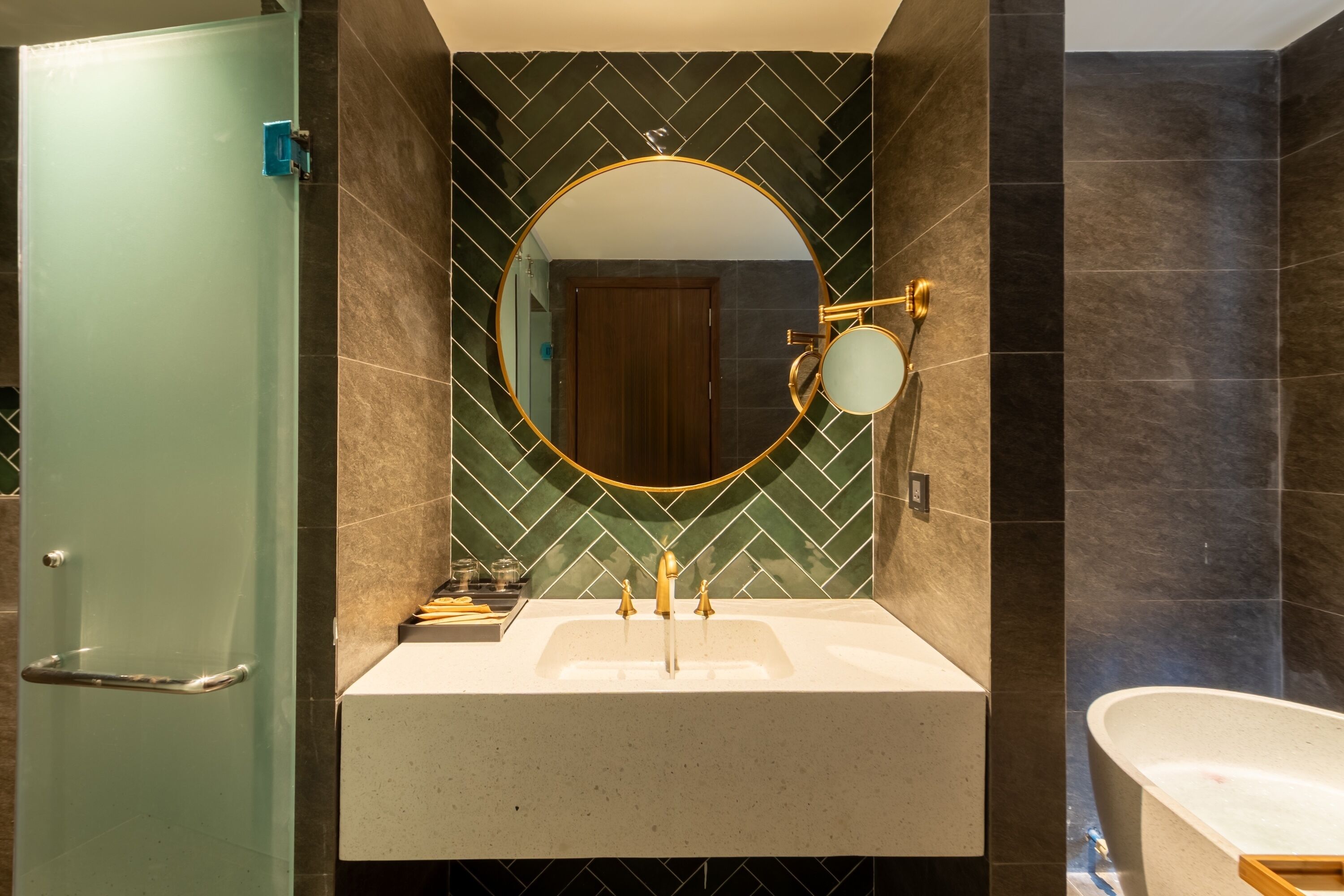 Un bagno con un lavandino bianco, uno specchio rotondo con cornice dorata e una vasca.