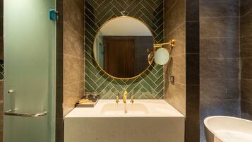 Un bagno con un lavandino bianco, uno specchio rotondo con cornice dorata e una vasca.
