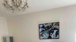 Une chambre à coucher moderne avec un grand lit, un lustre, un tableau et une table d’appoint.