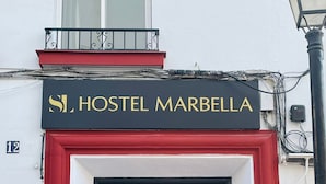 A building with a sign reading "HOSTEL MARBELLA" above a black door with a decorative glass panel. - SL Hostel Marbella (Marbella)