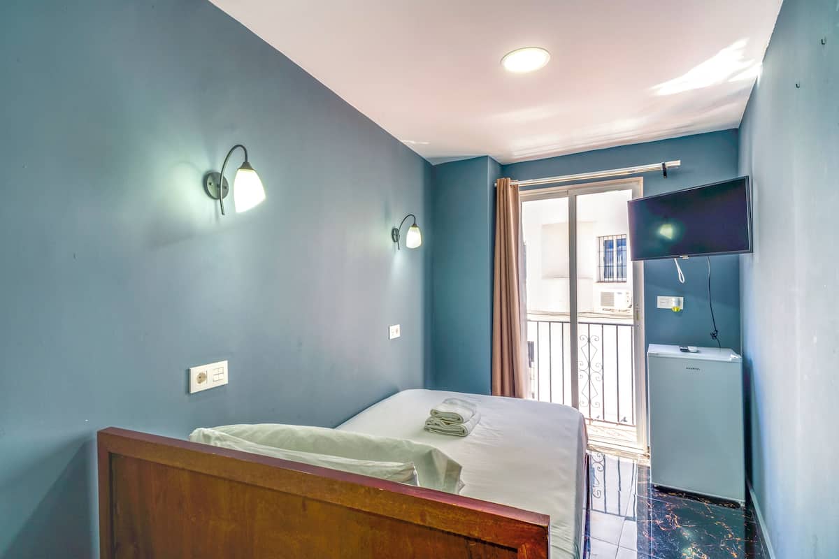 Een hotelkamer met een bed, een aan de muur bevestigde televisie en een koelkast.