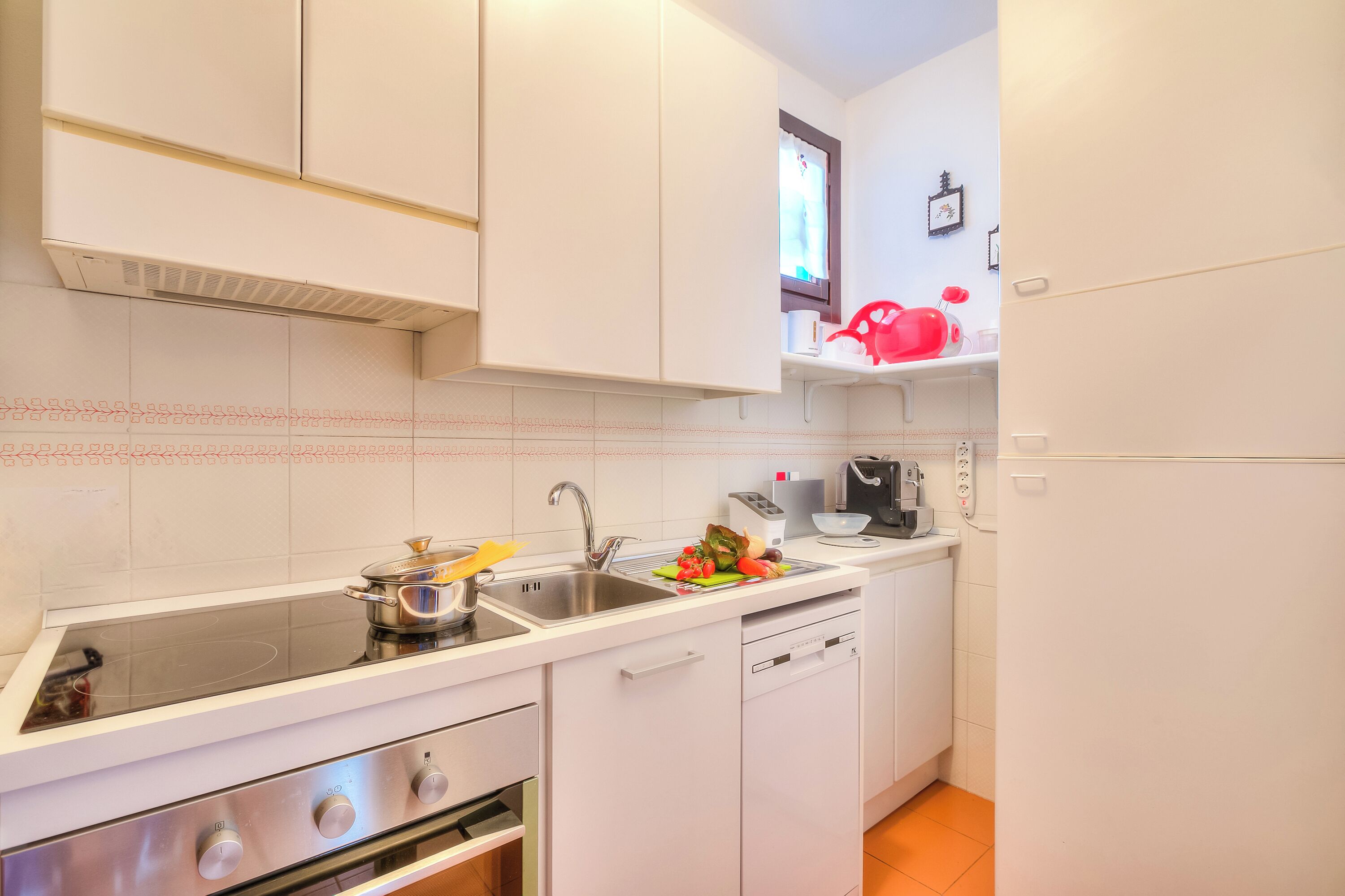 A compact kitchen with white cabinets, a stove, a dishwasher, and a sink.