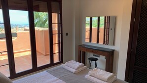 A bedroom with a bed, a desk, and a chair. There is a sliding glass door leading to an outdoor area. -  El Soto de Marbella F/F Penthouse P20 Sea/Mountain Views.Onsite Golf-Gym-Tennis (AN)