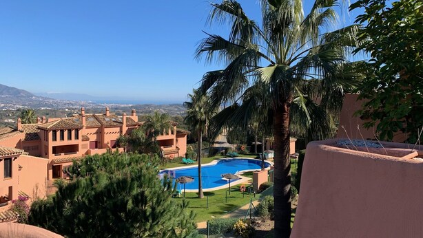 A pool surrounded by palm trees and a view of distant buildings. -  El Soto de Marbella F/F Penthouse P20 Sea/Mountain Views.Onsite Golf-Gym-Tennis (AN)