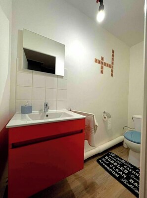 A bathroom with a white sink, red vanity, and a blue toilet.