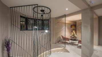 Ein modernes Interieur mit einer gebogenen Metallwand, einem Essbereich mit Tisch und Stühlen sowie einer Vase mit Blumen.
