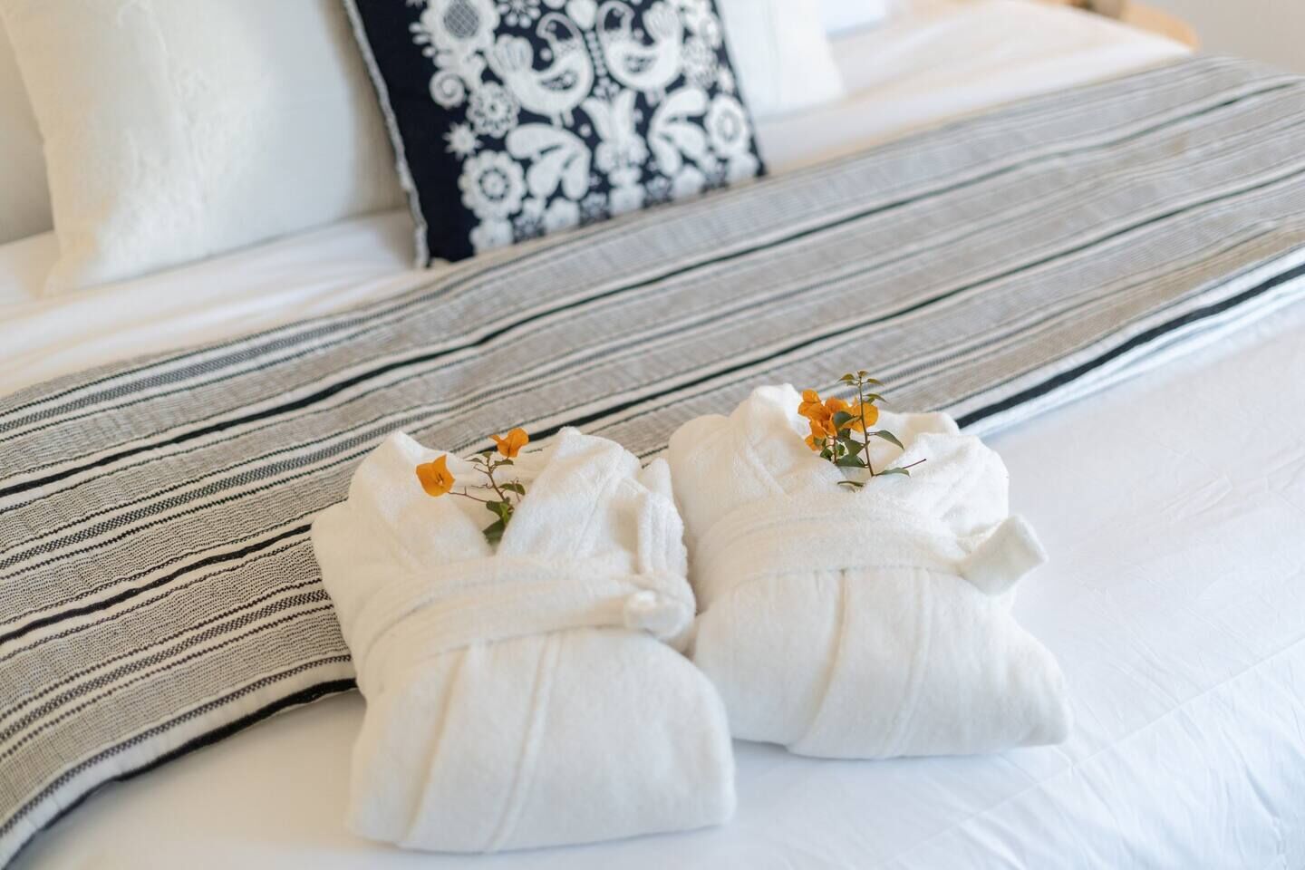 Un letto rifatto con lenzuola bianche e una coperta a righe.