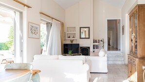 A spacious living room with a fireplace, a television, and a staircase leading to another level. - Kos Secret Villa with private pool (Kos)