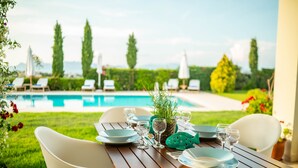A dining table set outdoors with a view of a swimming pool and lounge chairs in the background. - Kos Secret Villa with private pool (Kos)