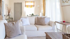 A living room with a white sofa, a wooden coffee table, and a dining area with a table and chairs. - Kos Secret Villa with private pool (Kos)