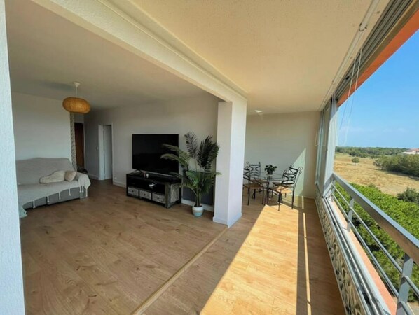 A spacious living area with a sofa, TV, and dining table.