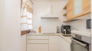 A modern kitchen with white cabinetry, a built-in oven, and a coffee machine. - Casa Lola by Wonderful Italy (Olbia)