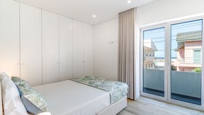 A bedroom with a bed, a wardrobe, a window with a view of buildings, and a curtain. - Oceanfront 3BR Apt 20m from calm Beach (Póvoa de Varzim)