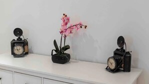 A white dresser with two black clocks and a potted orchid. - **** * Designer Apartment 18th (TOP 1) (Wien)