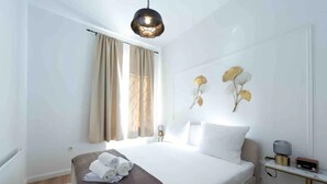 A hotel room with a bed, a bedside table with a lamp, a wall-mounted light fixture, and a window with curtains. - **** * Designer Apartment 18th (TOP 1) (Wien)