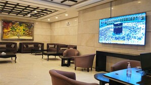 A hotel lobby with seating, a large TV screen, and a modern ceiling design. - Al Hidayah Towers Hotel (Makkah)