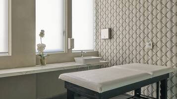 A clinical examination room with a bed, examination table, and a window with a view.