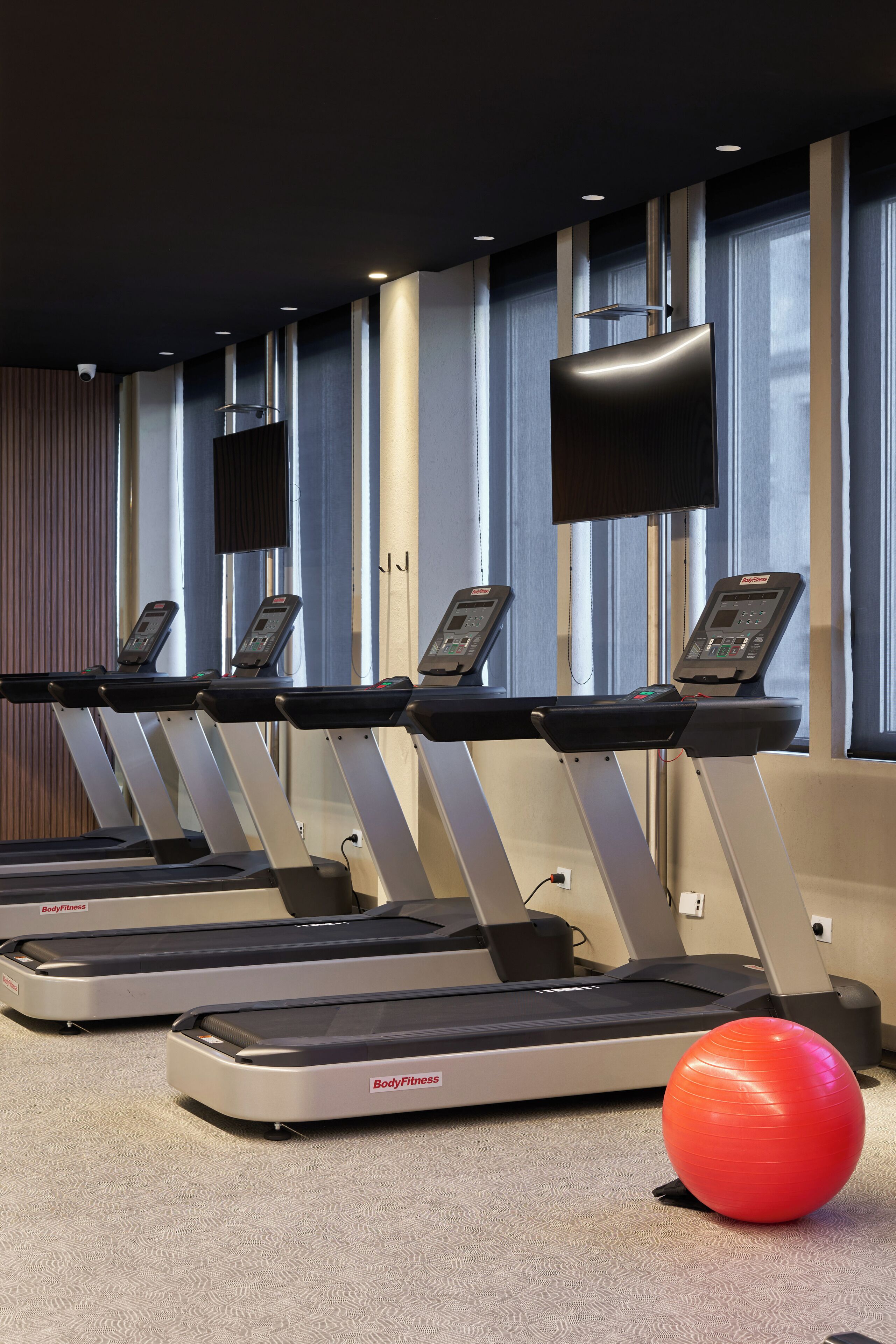 A gym with treadmills and a red exercise ball.