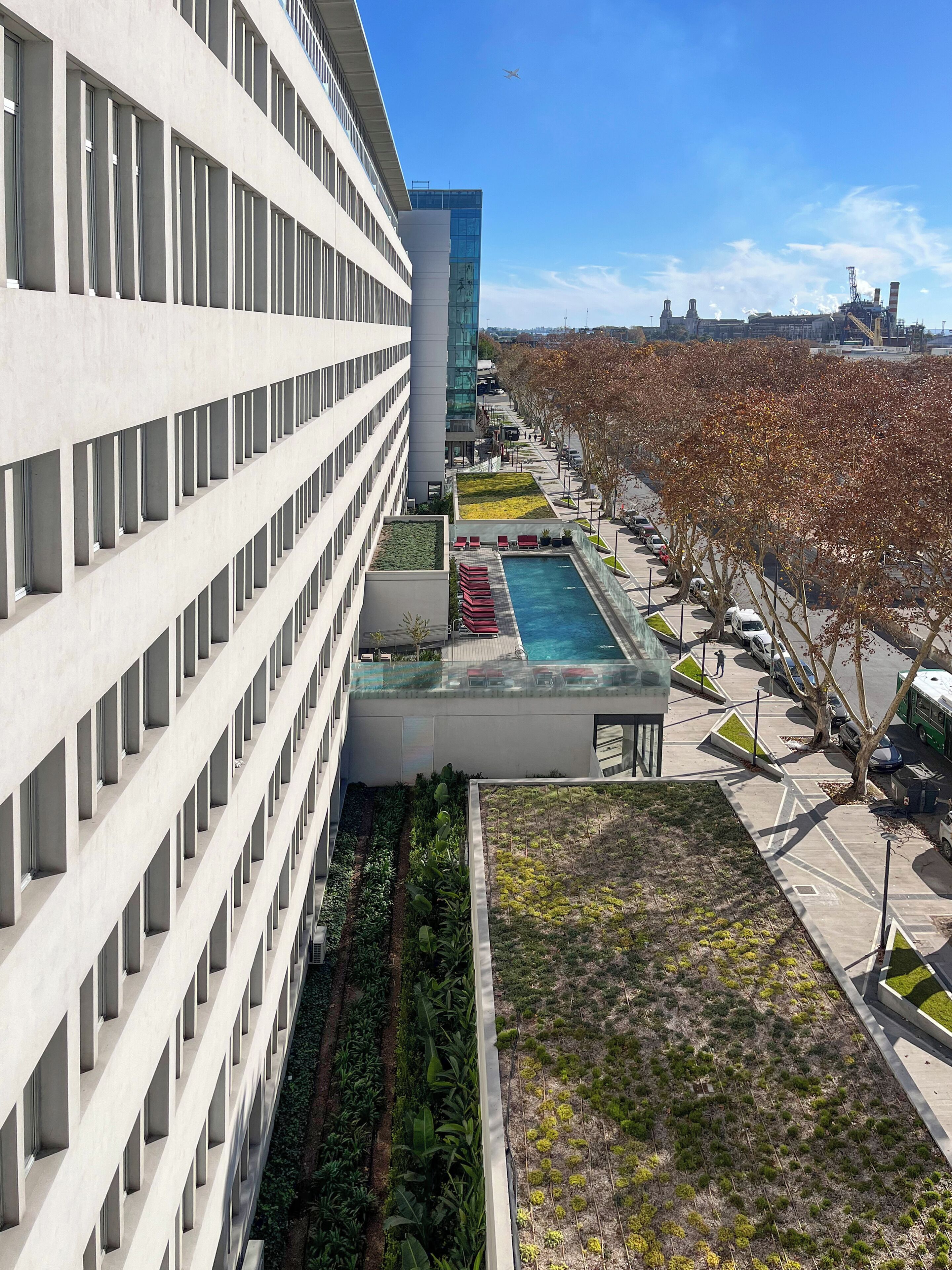 A modern building with a long, straight facade, a rooftop pool, and a green roof garden.