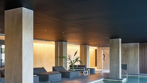 A modern indoor pool area with concrete pillars, seating, and a calm water surface. - Almarena Puerto Retiro Affiliated by Melia (Buenos Aires)
