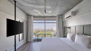 A modern hotel room with a large bed, a flat-screen TV, a balcony with a view of the city, and an air conditioning unit on the wall. - Almarena Puerto Retiro Affiliated by Melia (Buenos Aires)