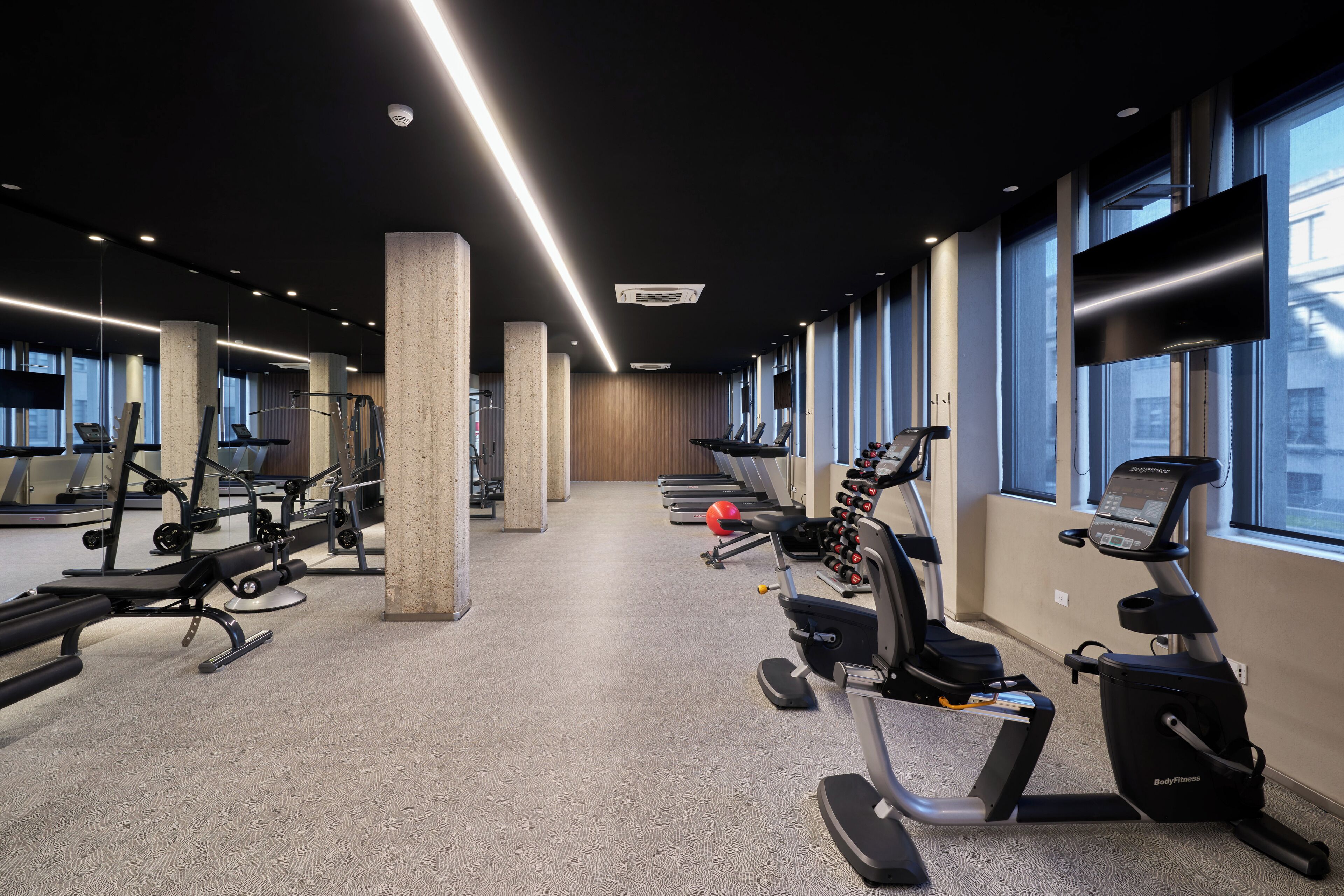 A gym with treadmills, elliptical machines, and weight stations.