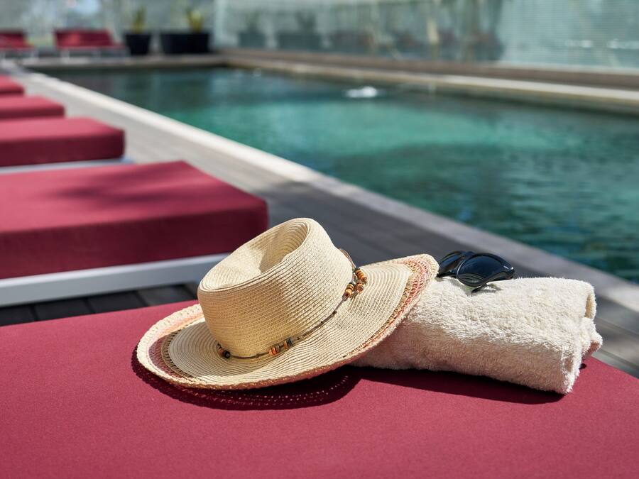 A poolside area with a lounge chair, a hat, and a towel.