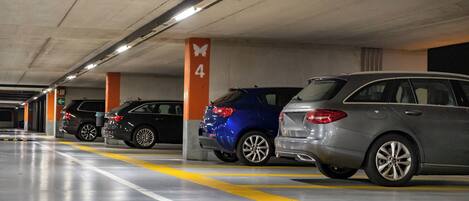 En parkeringskælder med flere biler parkeret på nummererede pladser, med pile der angiver vejvisning.