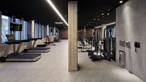 A modern gym with treadmills, weight machines, and a concrete pillar. - Almarena Puerto Retiro Affiliated by Melia (Buenos Aires)