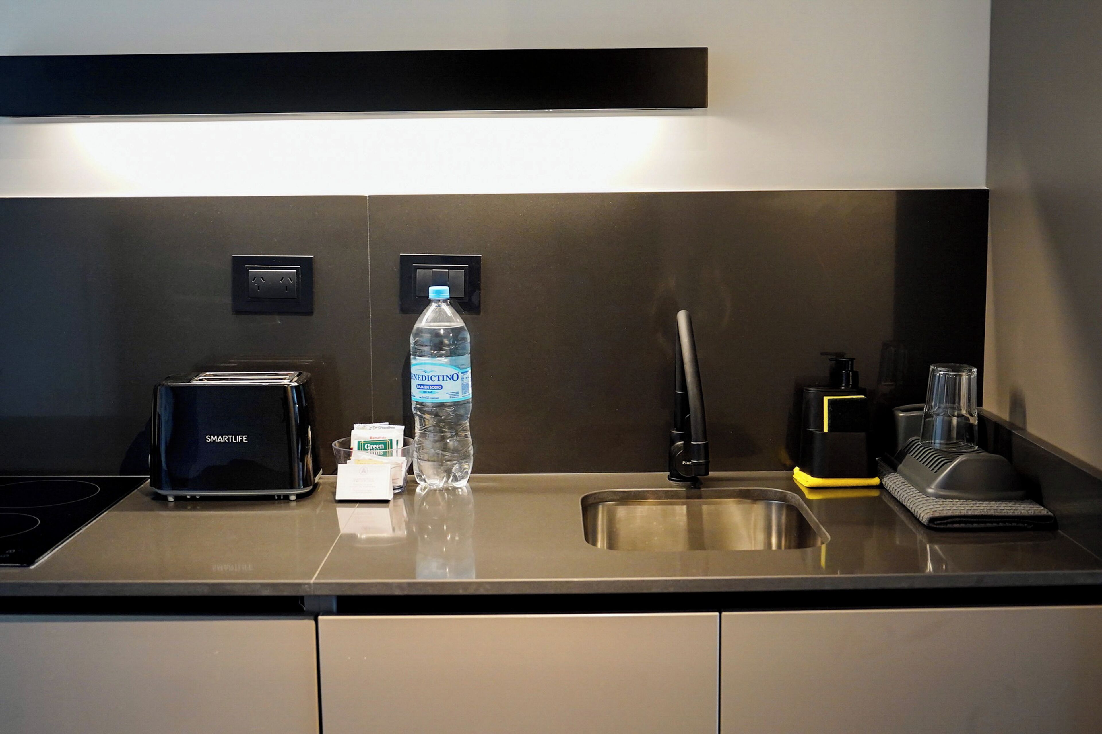 Una cocina moderna con tostadora, botella de agua, cafetera y lavabo.