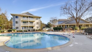 Ein Hotel mit Schwimmbad, Liegestühlen und einem Gebäude mit mehreren Balkonen.