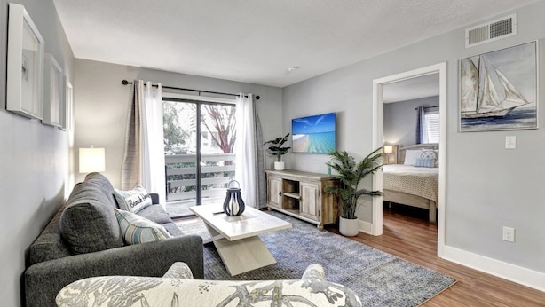 Ein modernes Wohnzimmer mit einer Couch, einem Couchtisch und Blick auf einen Balkon.