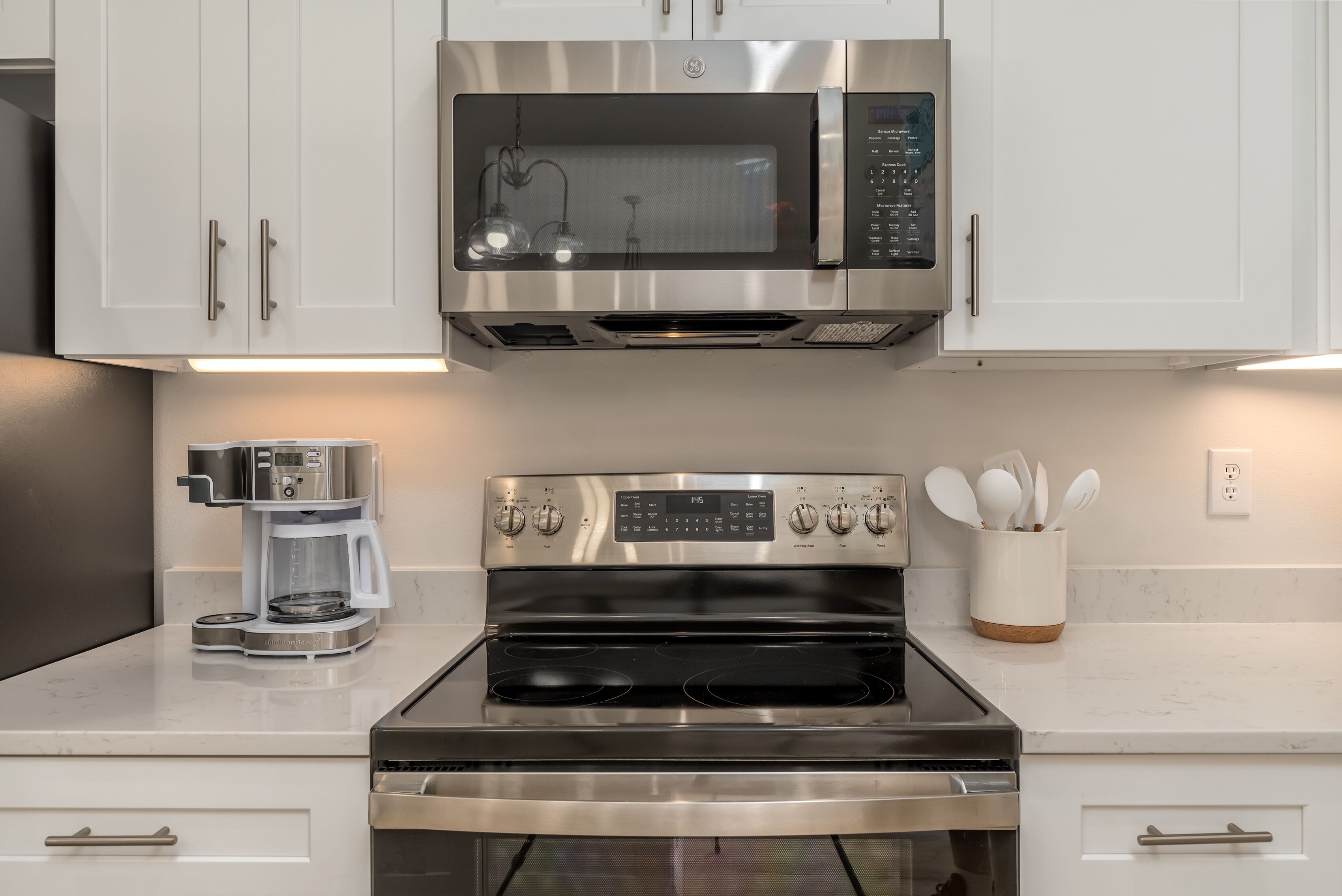 A kitchen with a stainless steel microwave, oven, and coffee maker.