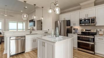 A modern kitchen with white cabinetry, stainless steel appliances, and pendant lighting.