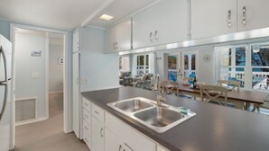 Una cocina moderna con una isla grande, electrodomésticos de acero inoxidable y vistas a la terraza exterior.