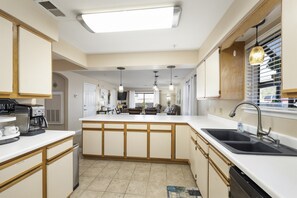A modern kitchen with a central island, white cabinetry, and a built-in dishwasher.