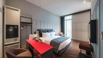 Una habitación de hotel moderna con una cama, un escritorio con cubierta roja, una silla, un televisor y una ventana con cortinas.