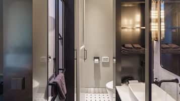 A modern bathroom with a large mirror, a white sink, and a shower area.