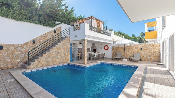 Una piscina con un muro de piedra y un balcón.