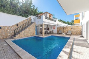 A swimming pool with a stone wall and a balcony.