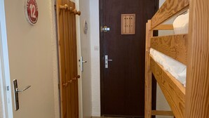 A narrow hallway with a wooden door, a bunk bed, and a wall-mounted sign. - Studio at the slopes, south balcony, parking (La Salle-les-Alpes)