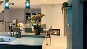 Een moderne keuken met een centraal eiland, hangende verlichting en een zithoek met een bank en stoelen.