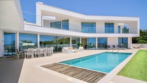 A modern two-story house with a swimming pool, outdoor seating, and large glass doors. - Ocean view Architectural Modern Villa (Luz)