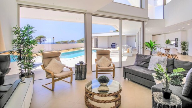 A modern living room with a pool view, large windows, and a dining area. - Ocean view Architectural Modern Villa (Luz)