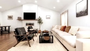 A modern living room with a flat-screen TV, a sofa, a coffee table, and a chair. - Cozy Escape! Modern/Luxe style w/2 Master en Suites-Fireplace-Fenced- SouthPark! (Charlotte)