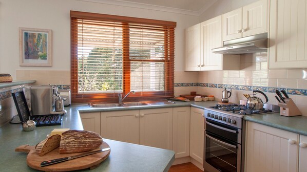 Kitchen equipped with double oven, stainless steel range hood, and ample counter space for meal preparation.