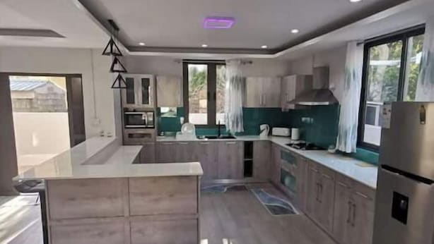 A modern kitchen with a central island, built-in appliances, and large windows. - Splendid 4-bedrooms villa private pool near beach (Flic en Flac)