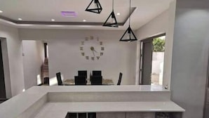 A modern kitchen with a central island, pendant lighting, and a clock on the wall. - Splendid 4-bedrooms villa private pool near beach (Flic en Flac)
